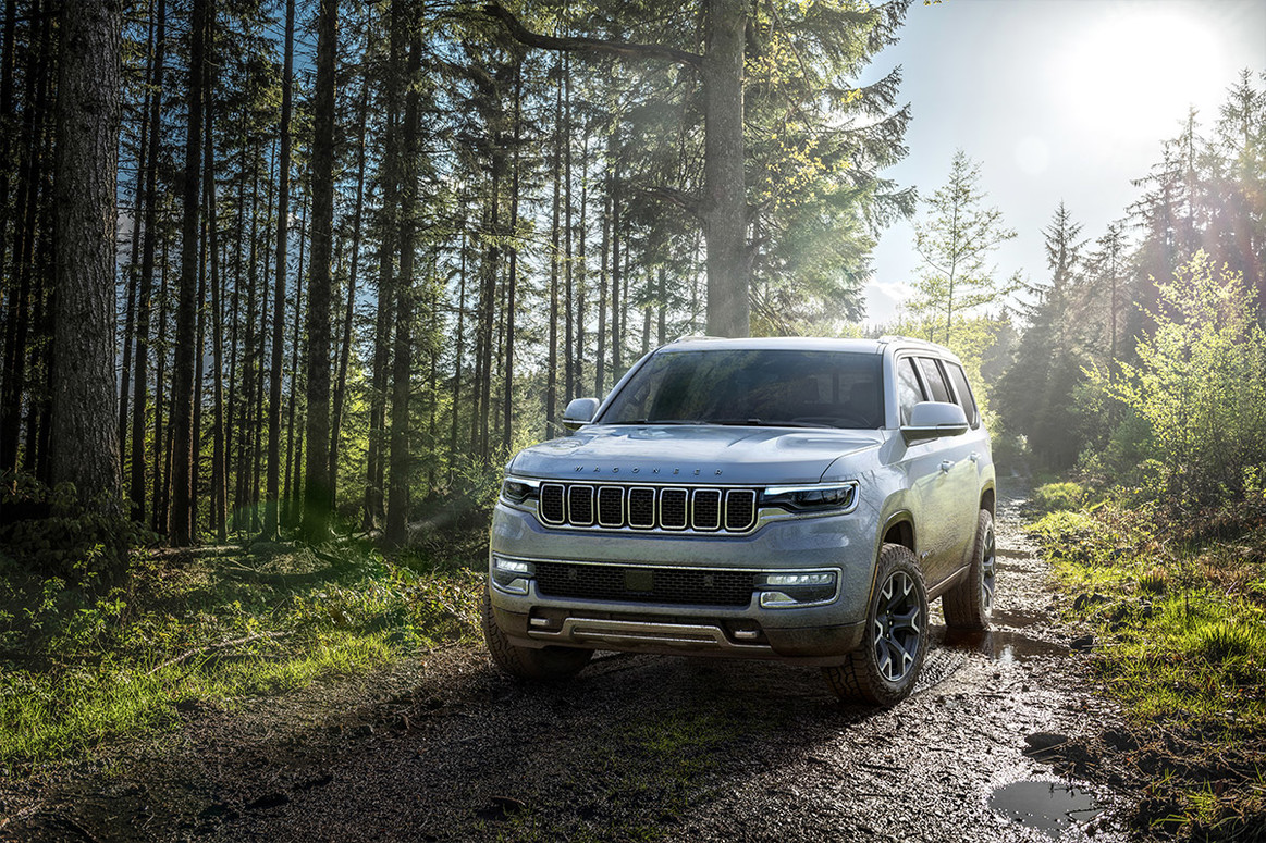 Un Wagoneer blanc 2022 garé dans une forêt sur un chemin de terre.