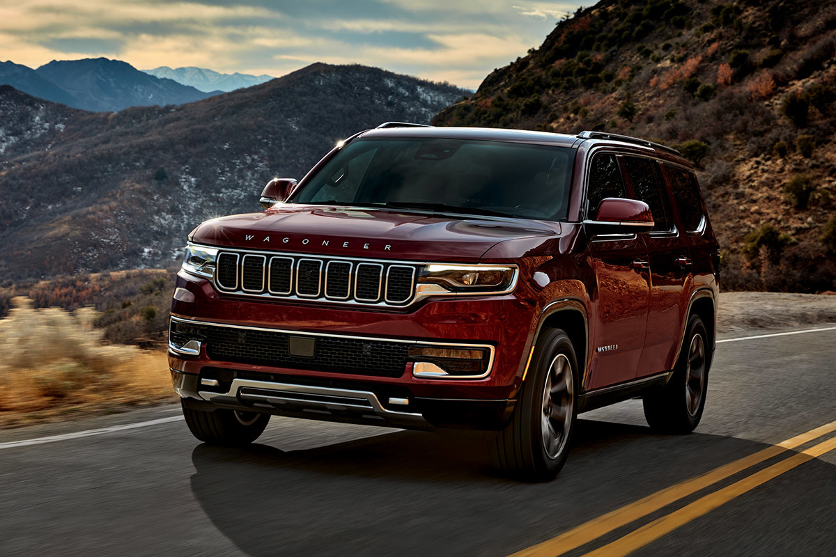 A red 2022 Wagoneer being driven on a freeway through the mountains.