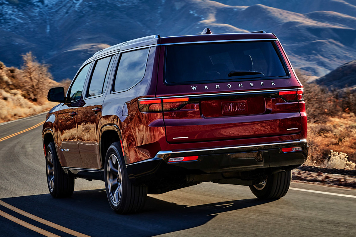 Un Wagoneer rouge 2022 conduit sur une route sinueuse à travers les montagnes.