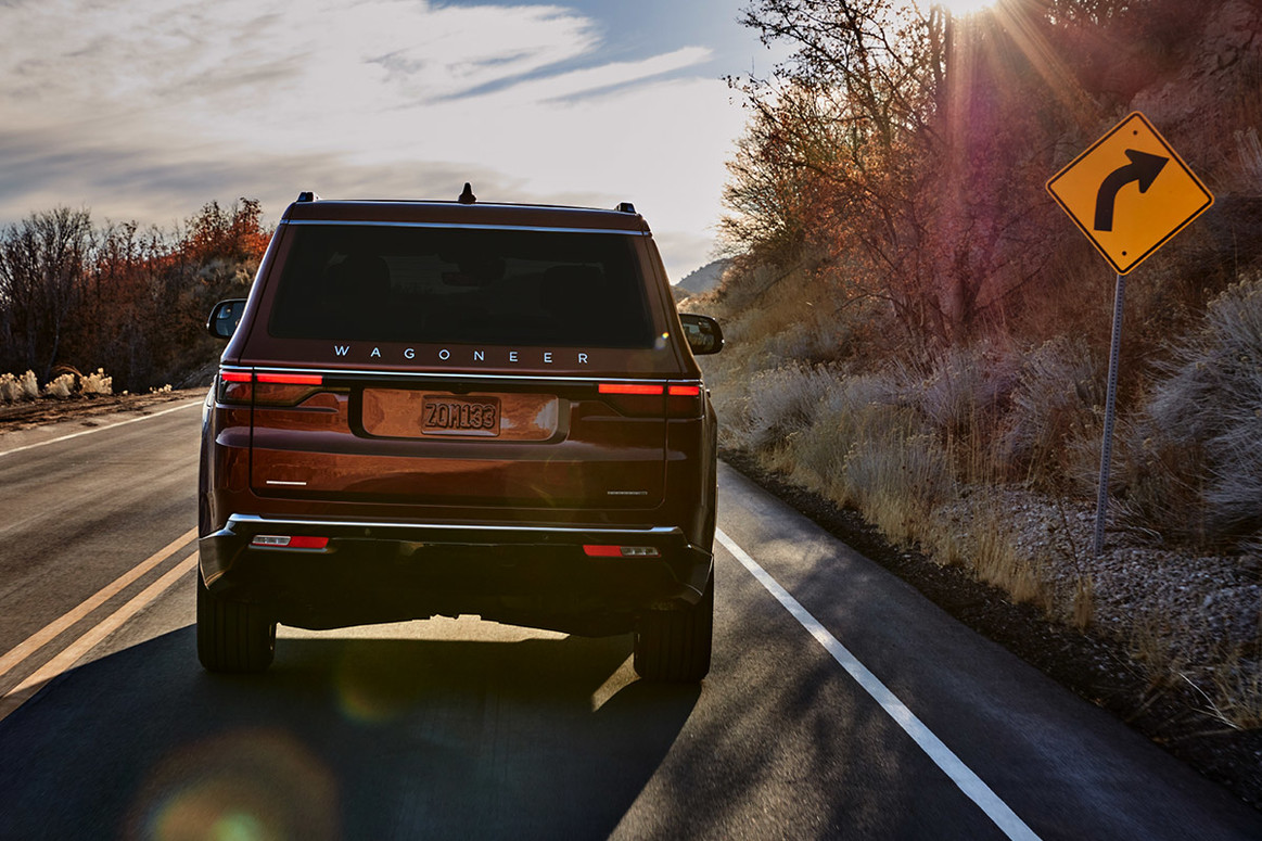 Un Wagoneer rouge 2022 roulant sur une route à travers les montagnes.