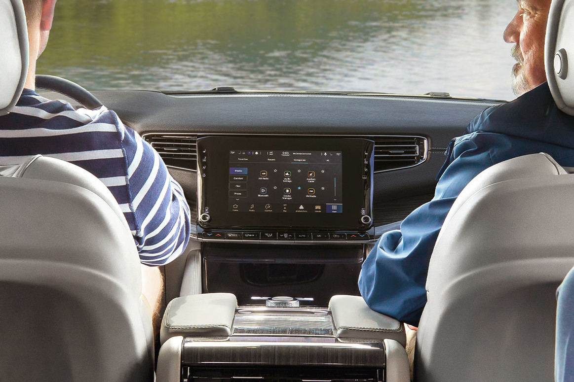 Two people sitting inside a 2022 Wagoneer, with the 10.1-inch touchscreen displaying various apps.