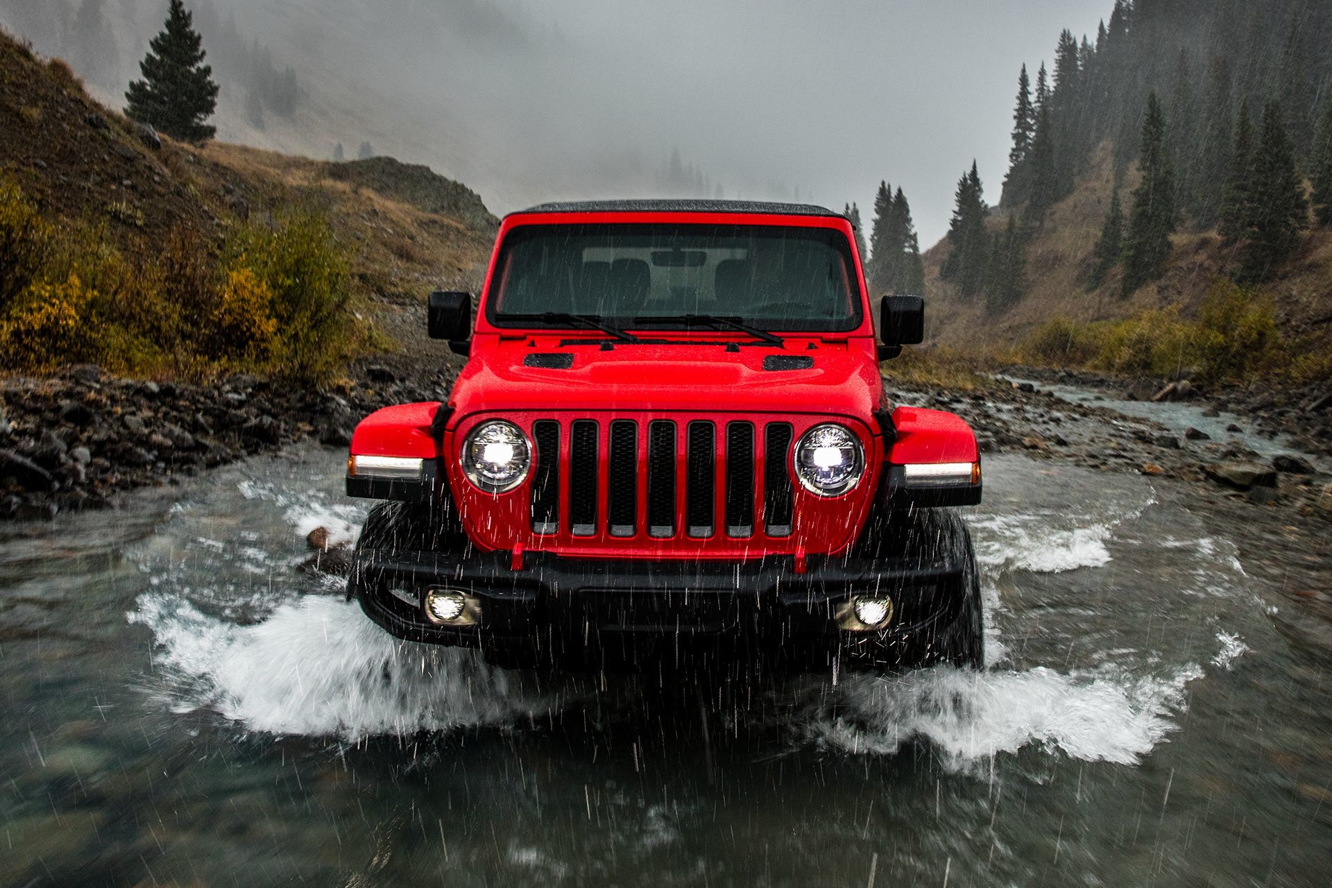 2018 Jeep Wrangler JL shown in red, driving through water