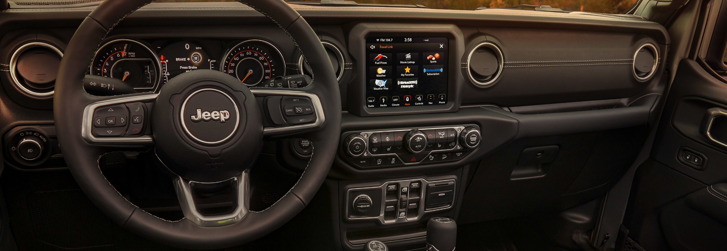 Interior view of a Jeep Wrangler including the steering wheel and entertainment system