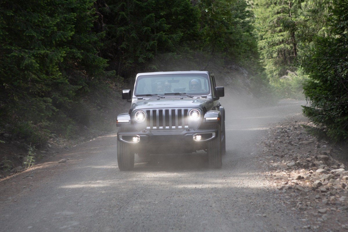 The silver 2020 Jeep Wrangler driving through trees in a mountain