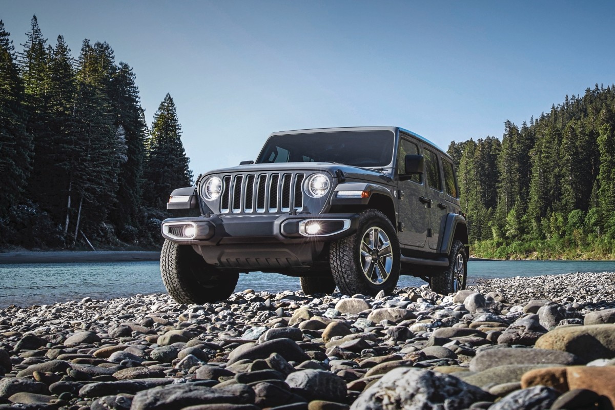 The green 2020 Jeep Wrangler driving through stream in a mountain