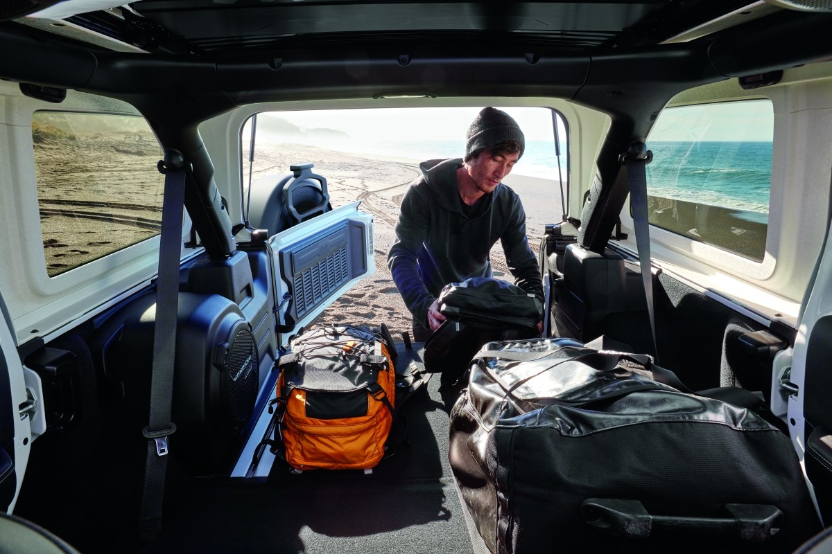 Man unloading cargo from the trunk of the 2020 Jeep Wrangler at a beach