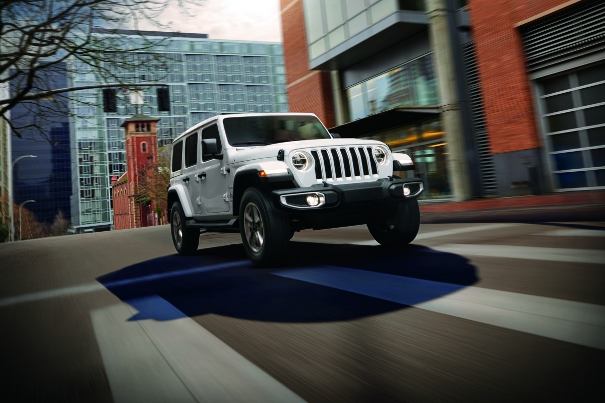 The white 2020 Jeep Wrangler being driven on a road in an urban area
