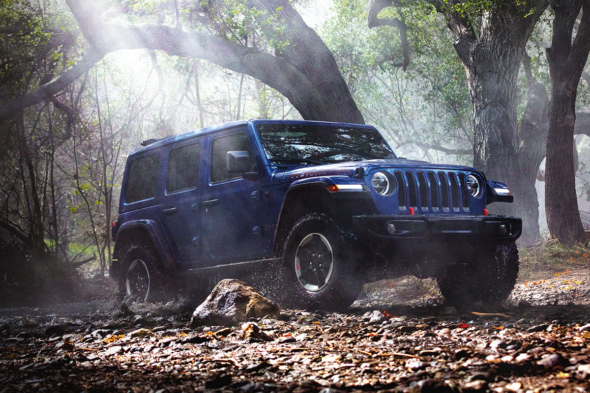 Vue avant inférieure d’un Wrangler 2020 bleu roulant en forêt dans une montagne