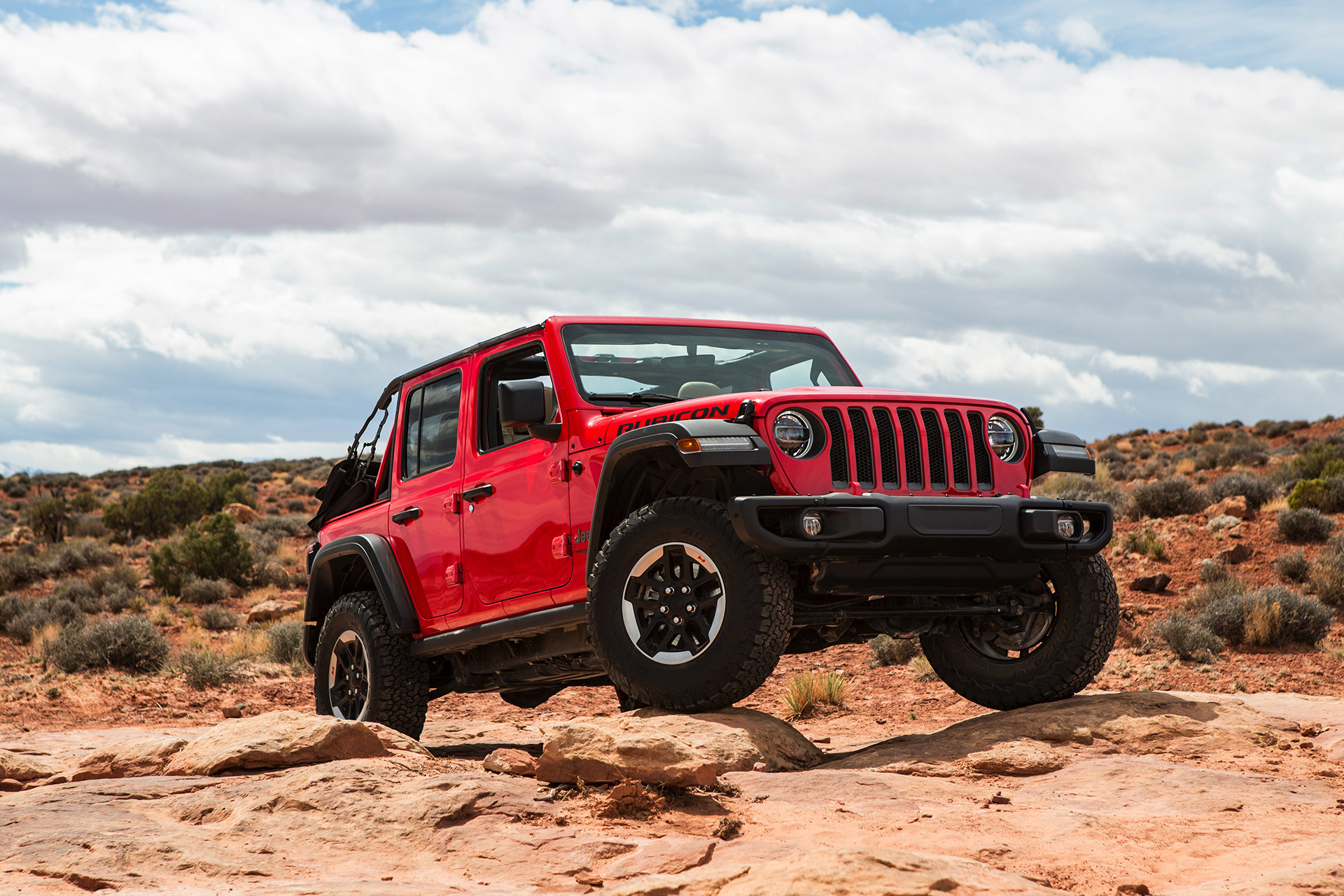 The red 2020 Jeep Wrangler driving through rocks in a desert