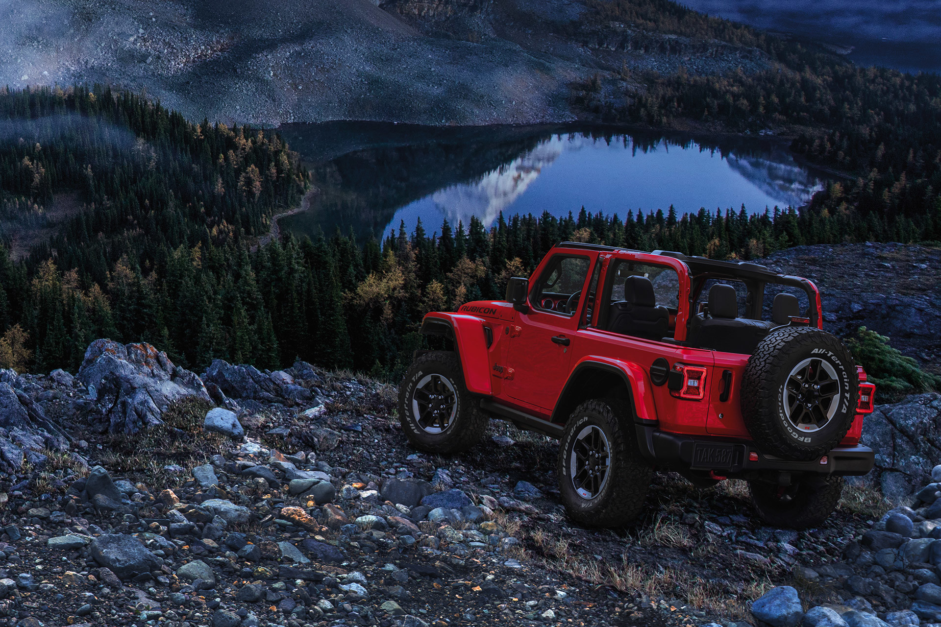 The red 2020 Jeep Wrangler parked outdoors facing lakes and mountains