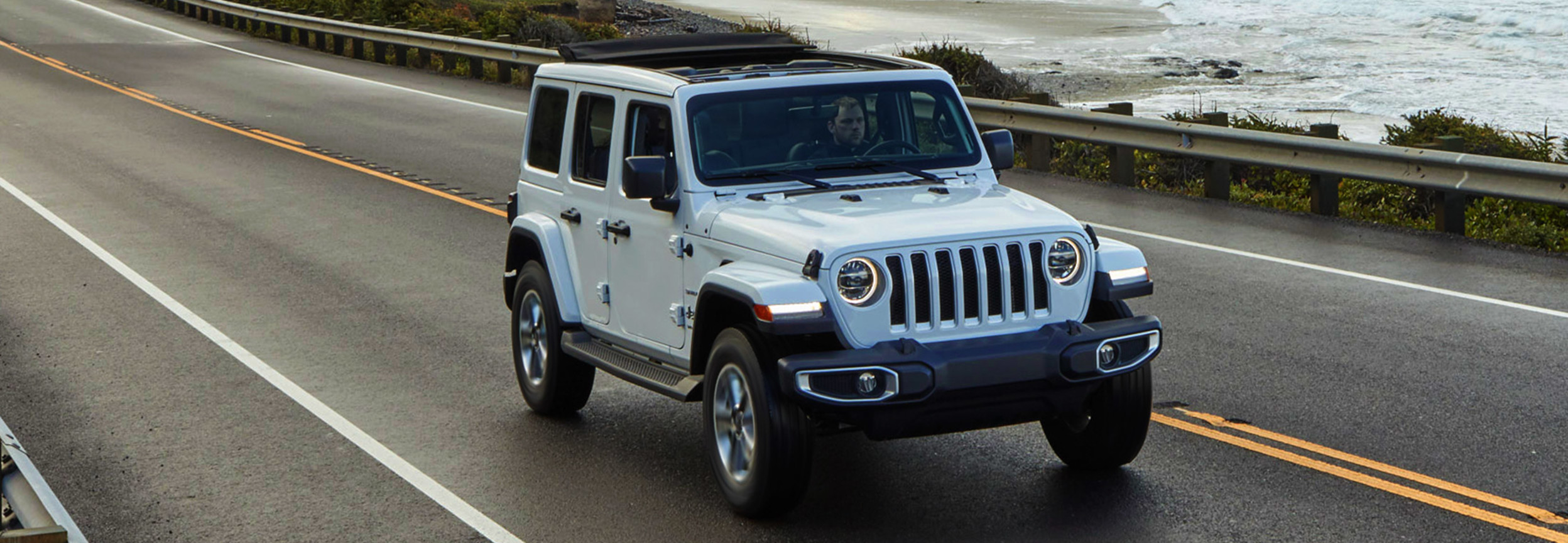 Jeep Wrangler 2021 blanc circulant sur une autoroute du front de mer.