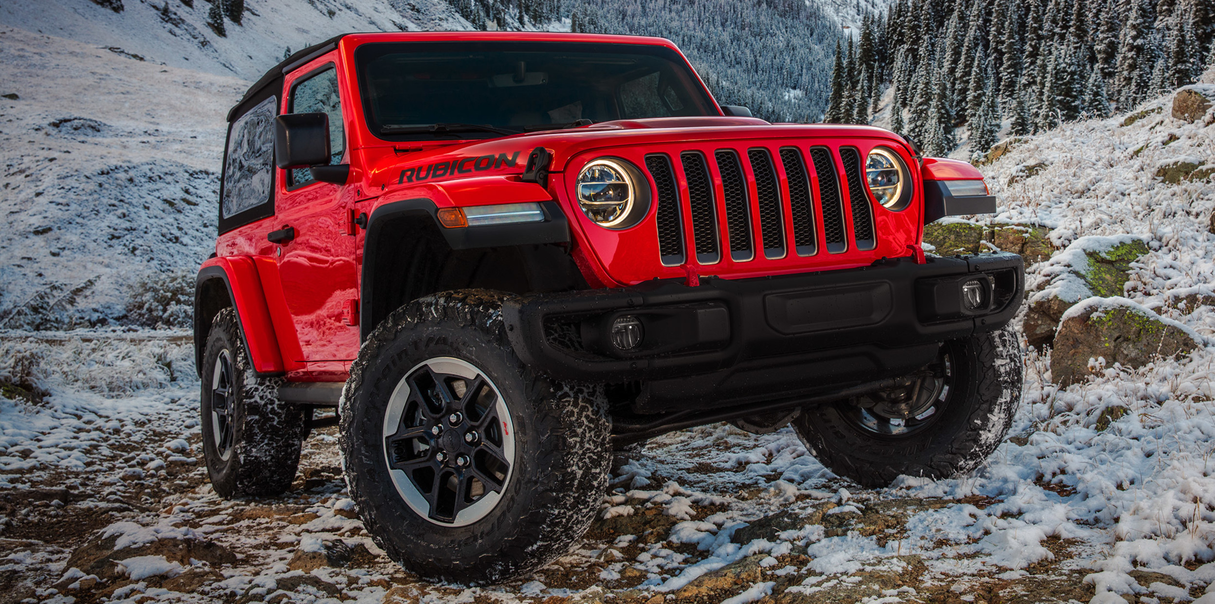 Red 2021 Jeep Wrangler on rocky mountain terrain.