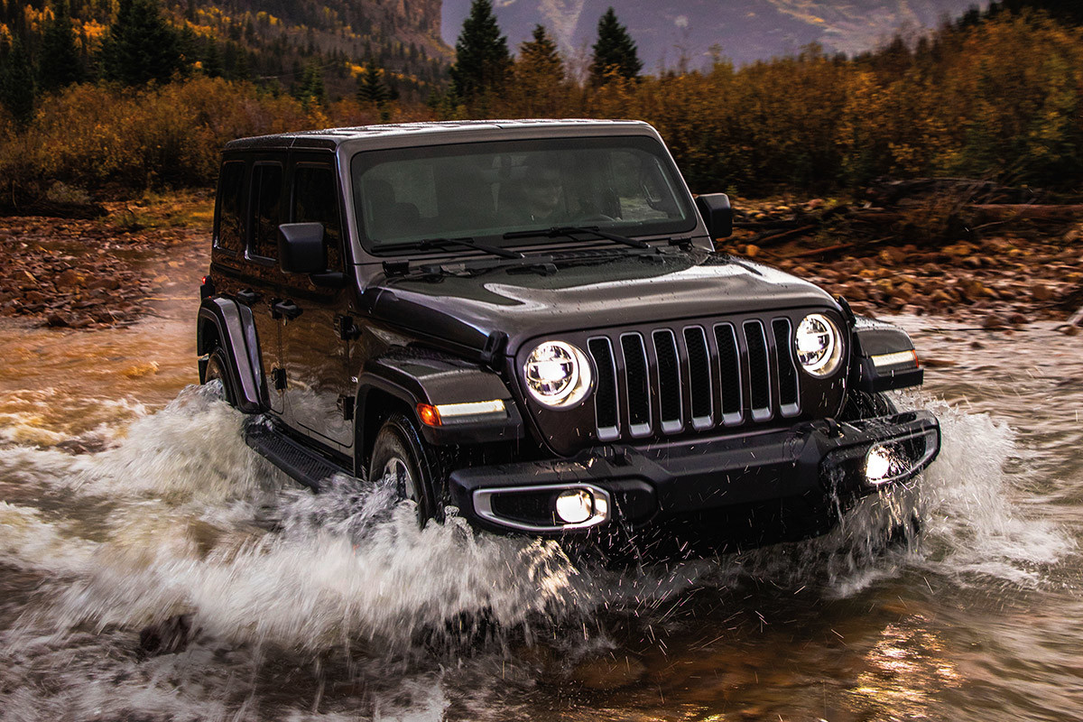 Jeep Wrangler 2021 noir traversant un ruisseau de montagne.