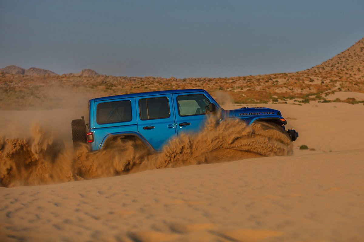 Vue latérale du Jeep Wrangler Rubicon 392 bleu en montée dans le désert.
