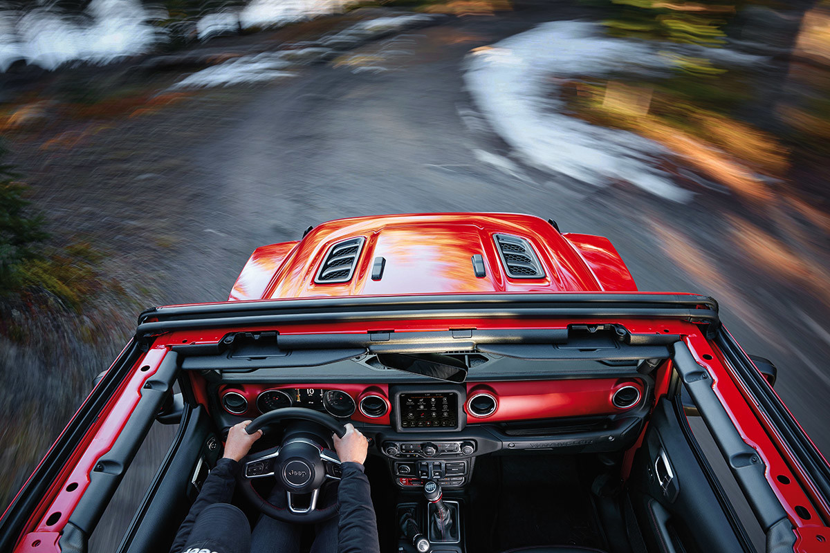 Top view of a person driving a red 2021 Jeep Wrangler with roof and windshield removed to let in the fresh country air.