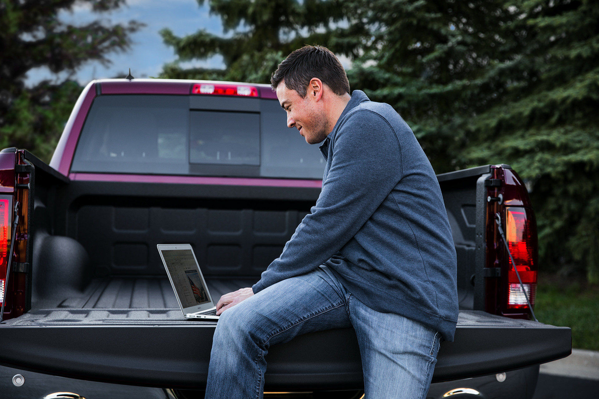Vue d'un homme utilisant un ordinateur portatif sur la caisse, à l'arrière du Ram 1500 Classic 2019