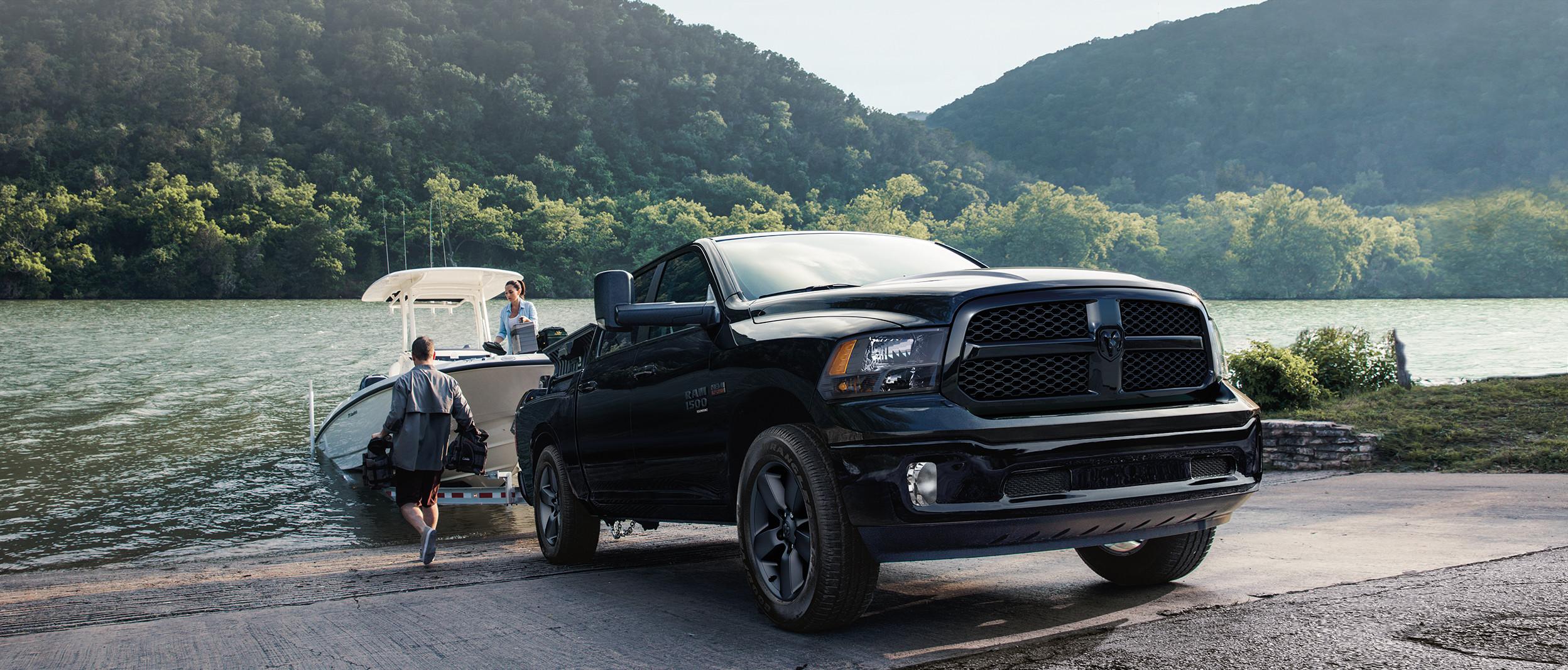 Ram 1500 Classic 2019 noir remorquant un bateau hors d’une rivière.