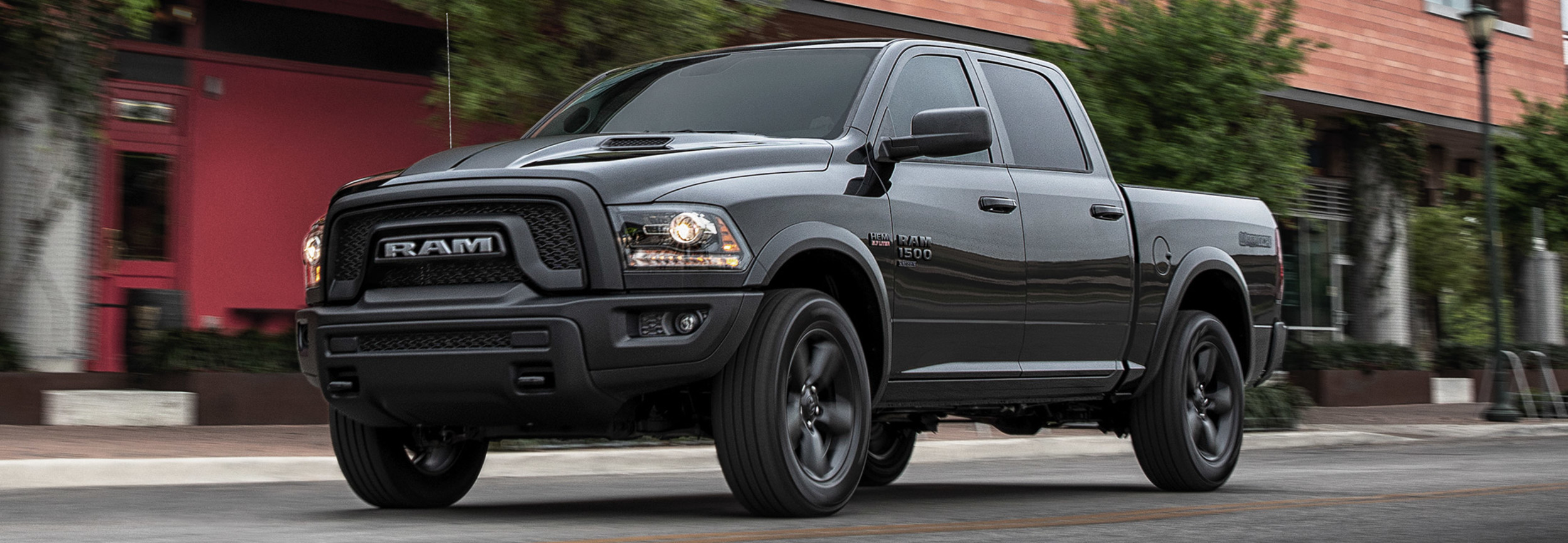Side view of a black RAM 1500 Classic driving past a building