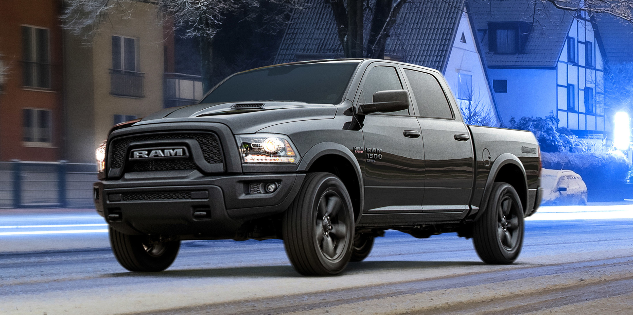 Ram 1500 DS noir roulant sur une route résidentielle calme, un lampadaire étant allumé au-dessus du véhicule.