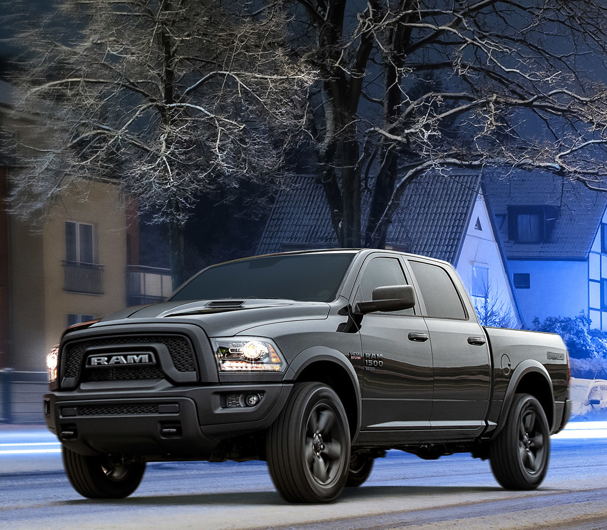 Ram 1500 DS noir roulant sur une route résidentielle calme, un lampadaire étant allumé au-dessus du véhicule.