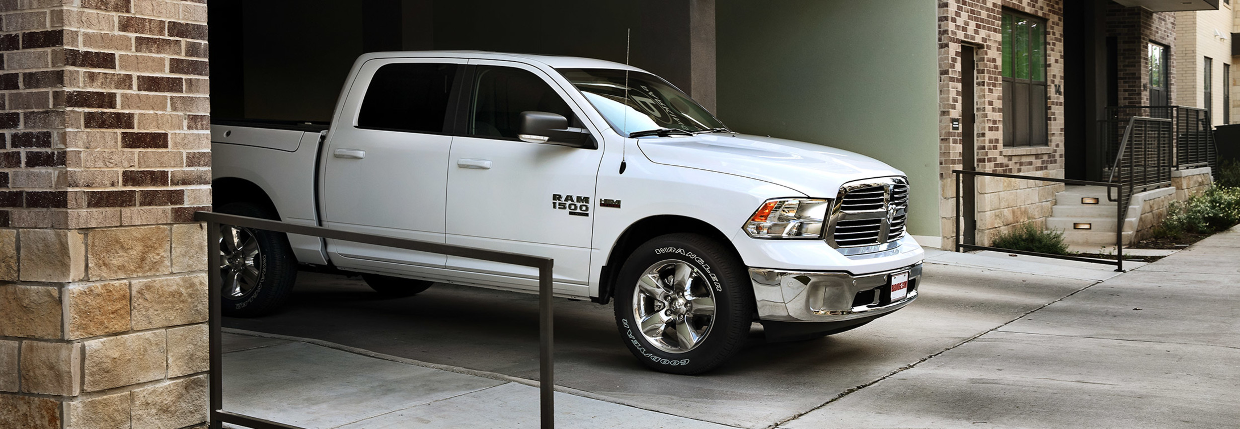 A side view of a Bright White 2021 Ram 1500 Classic being driven out of a parking garage.