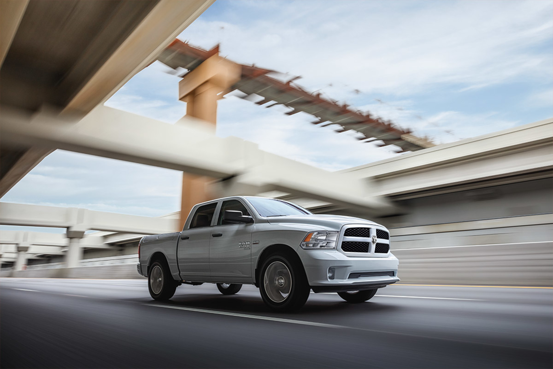 A side view of a Billet Metallic 2021 Ram 1500 Classicbeing driven on a highway underpass.