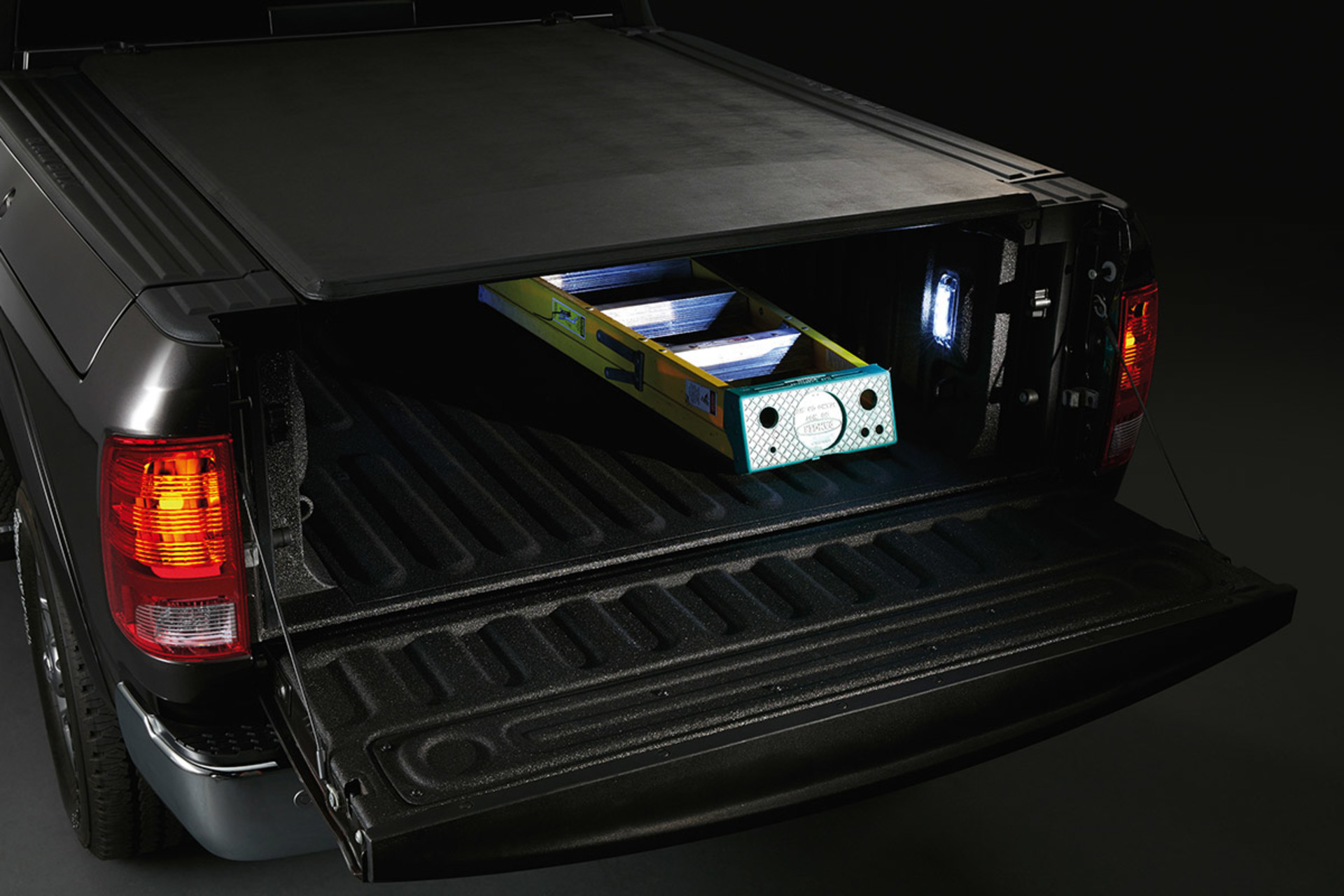A rear view of a 2021 Ram 1500 Classic with the tailgate folded down to reveal a ladder and available LED lighting on the side of the cargo bed.