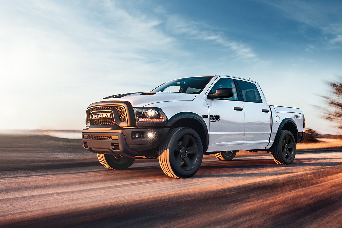 A white 2022 Ram 1500 Classic being driven on a road outdoors.