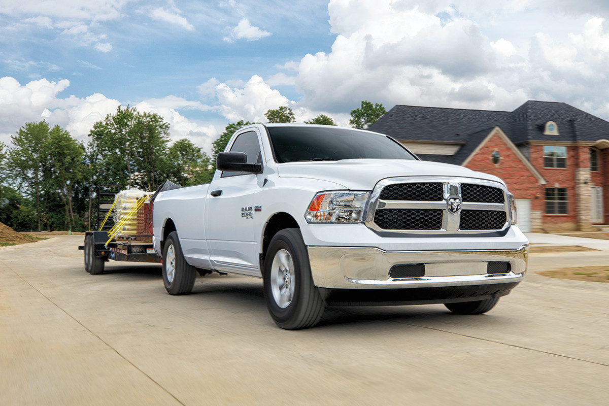 A white 2022 Ram 1500 Classic, towing various materials on a flatbed trailer.