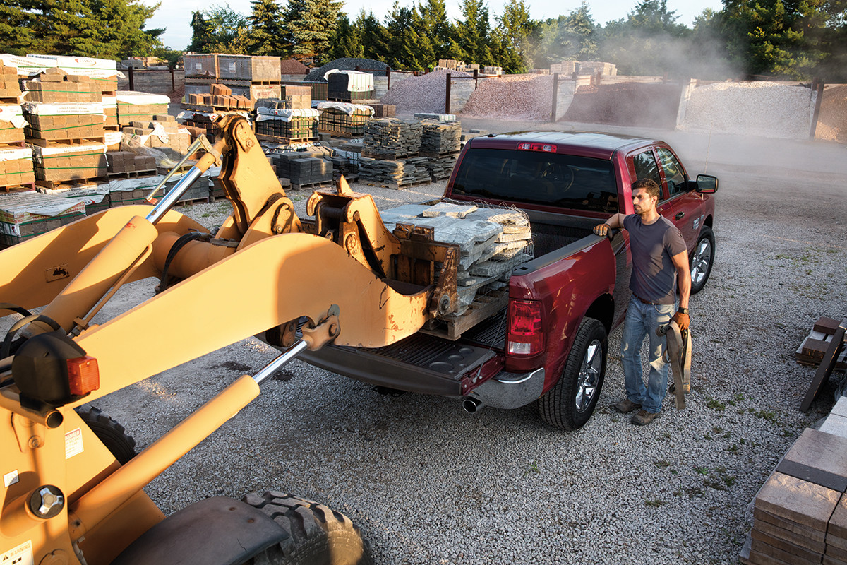 A red 2022 Ram 1500 Classic, with the bed being loaded with pieces of concrete.