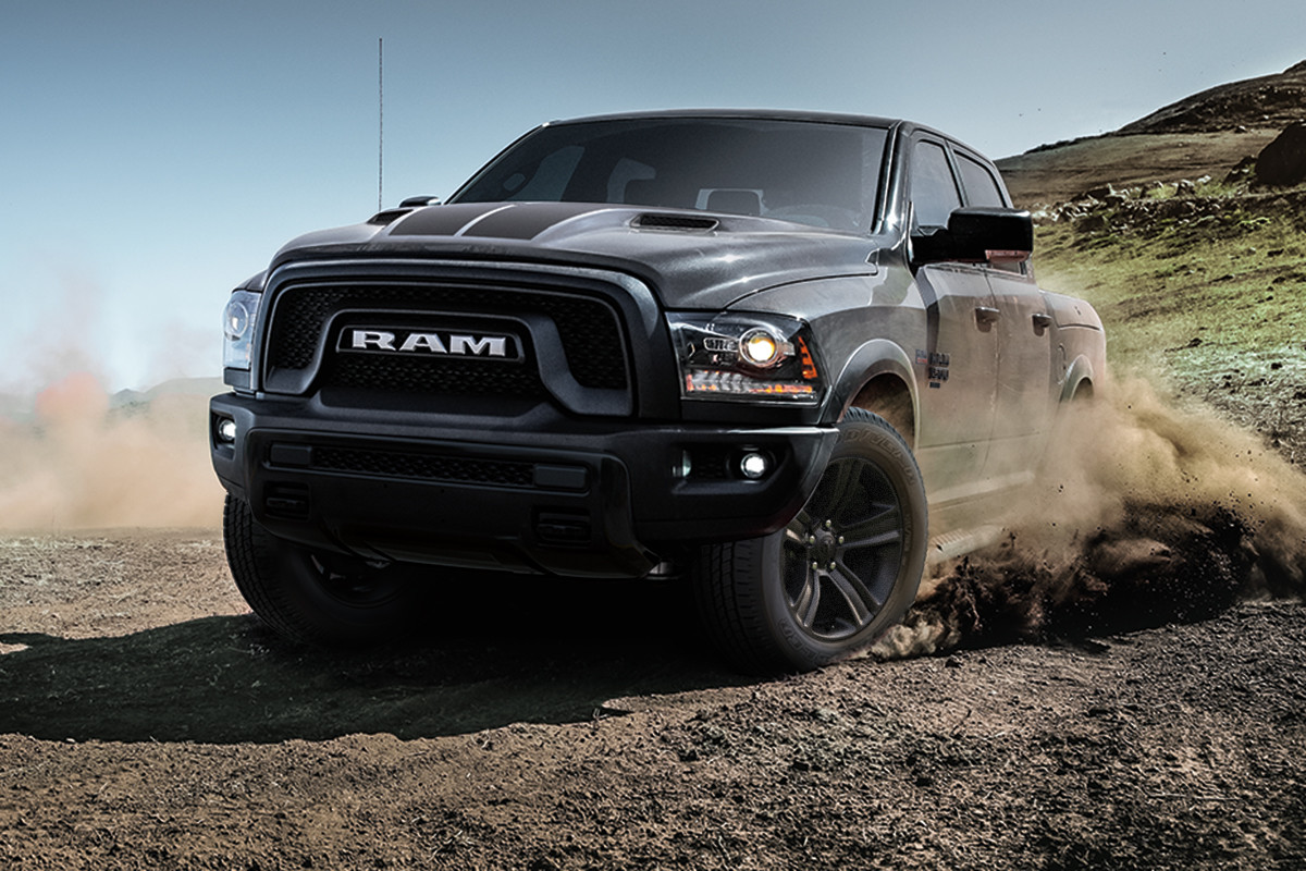A black 2022 Ram 1500 Classic being driven on dirt, with a grassy mountain in the background.