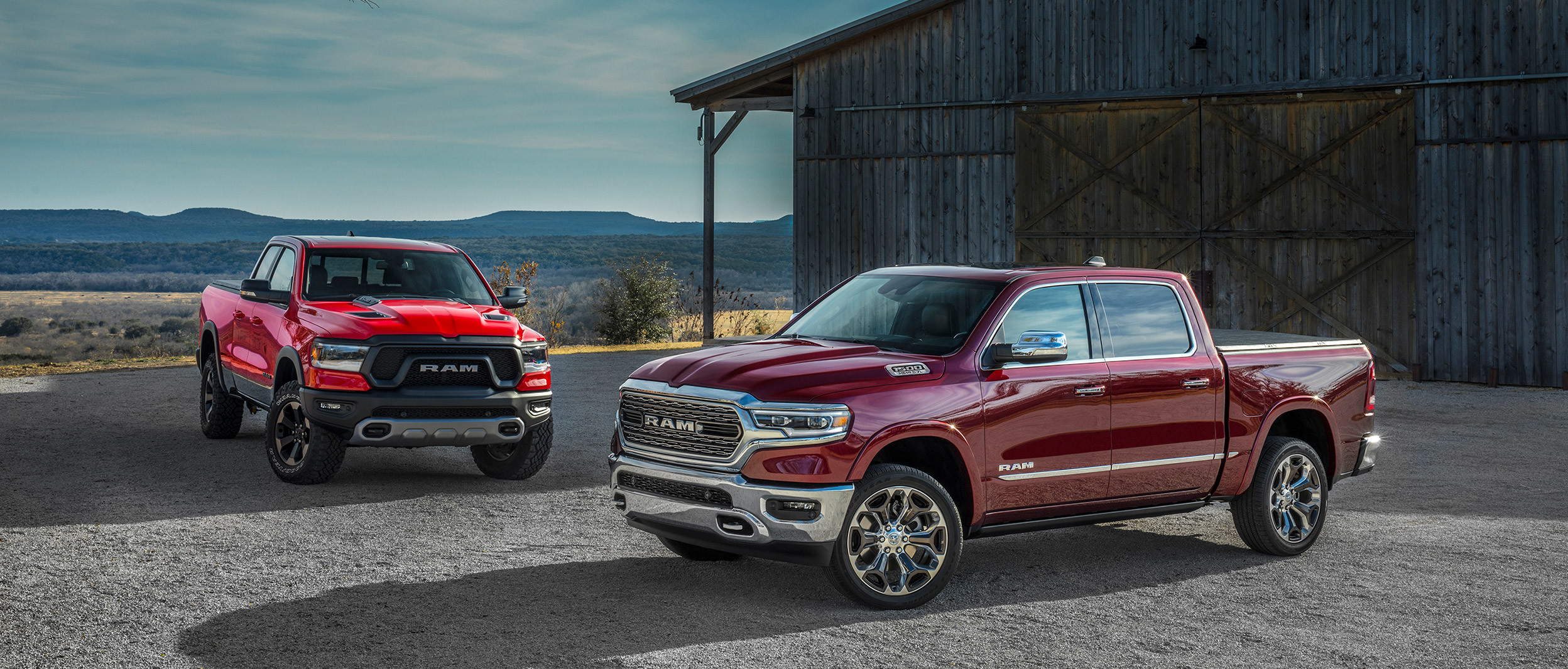 Two 2020 Ram 1500 parked in front of a barn.