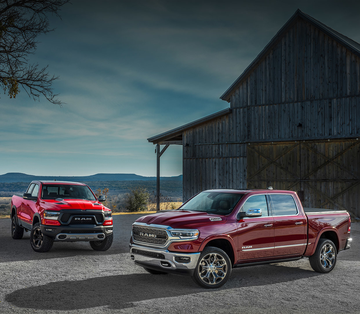 Two 2020 Ram 1500 parked in front of a barn.