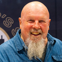 A bearded man smiling and looking at the camera in an interview setting.