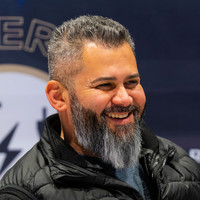 A bearded man smiling and looking at the camera in an interview setting.