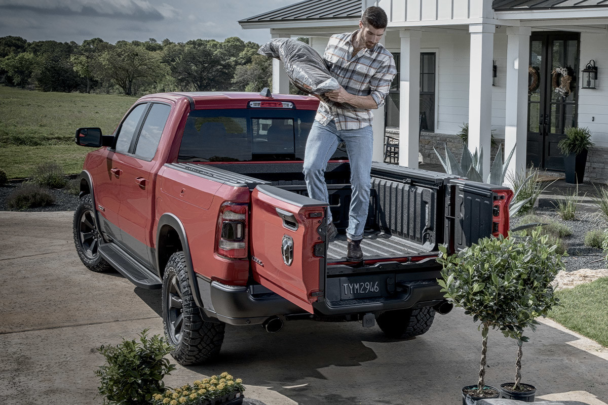 Ram 1500 2022 rouge montrant le hayon divisé 60-40 unique devant une maison.