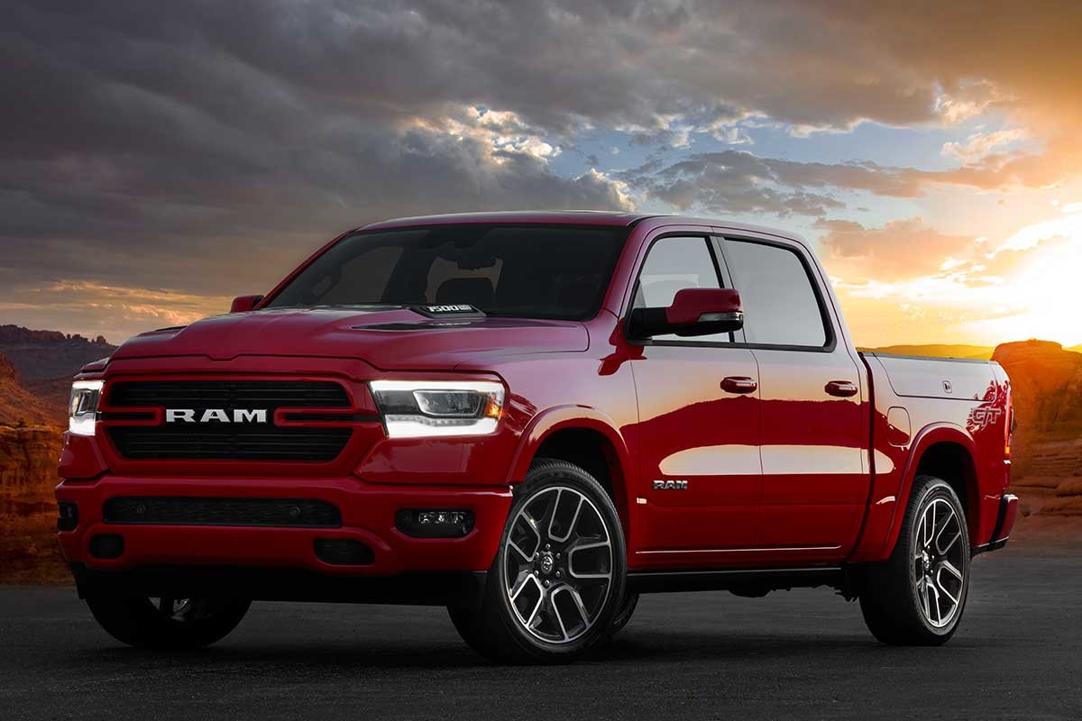 2022 Ram 1500 Laramie G/T en rouge flamboyant garé sur l'asphalte au crépuscule avec la mesa et le ciel nuageux au loin.