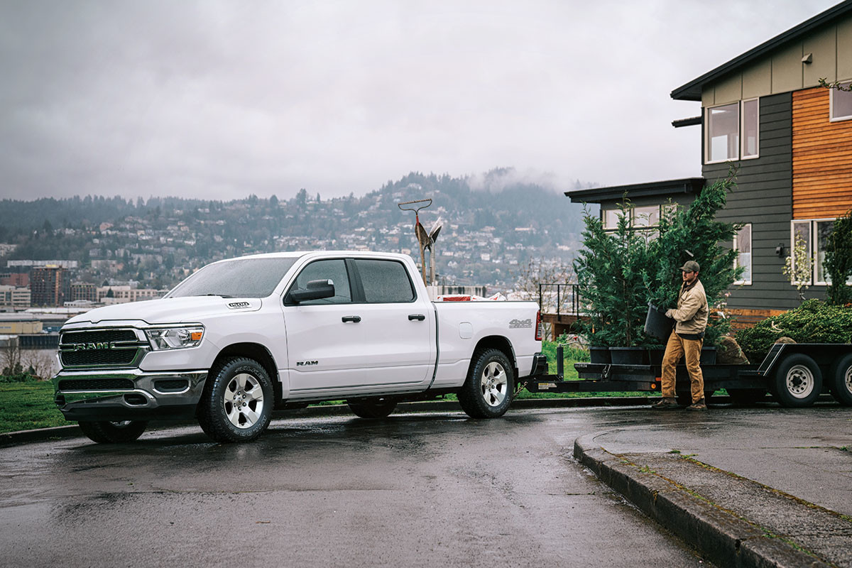 Un Ram 1500 2023 blanc tirant une remorque à plateau.