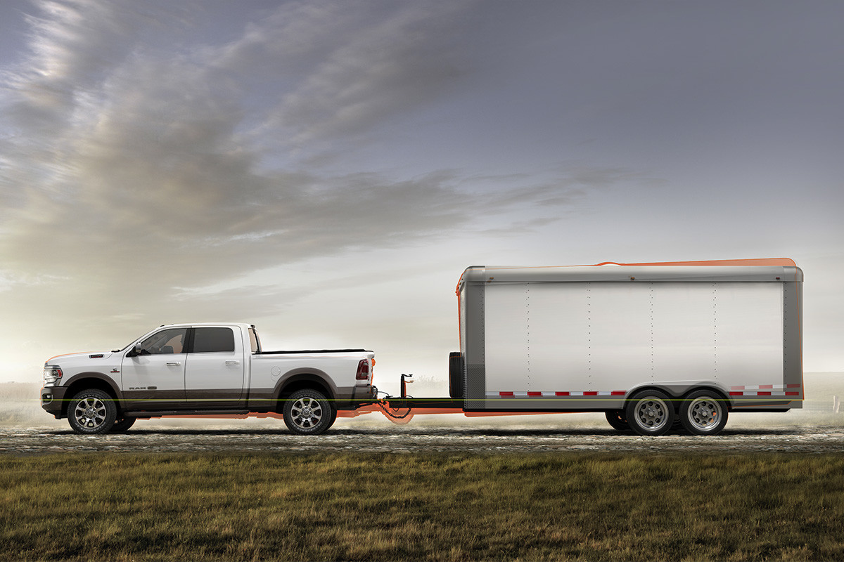 Side view of the new 2019 Ram 2500 white towing a trailer parked on a countryside road