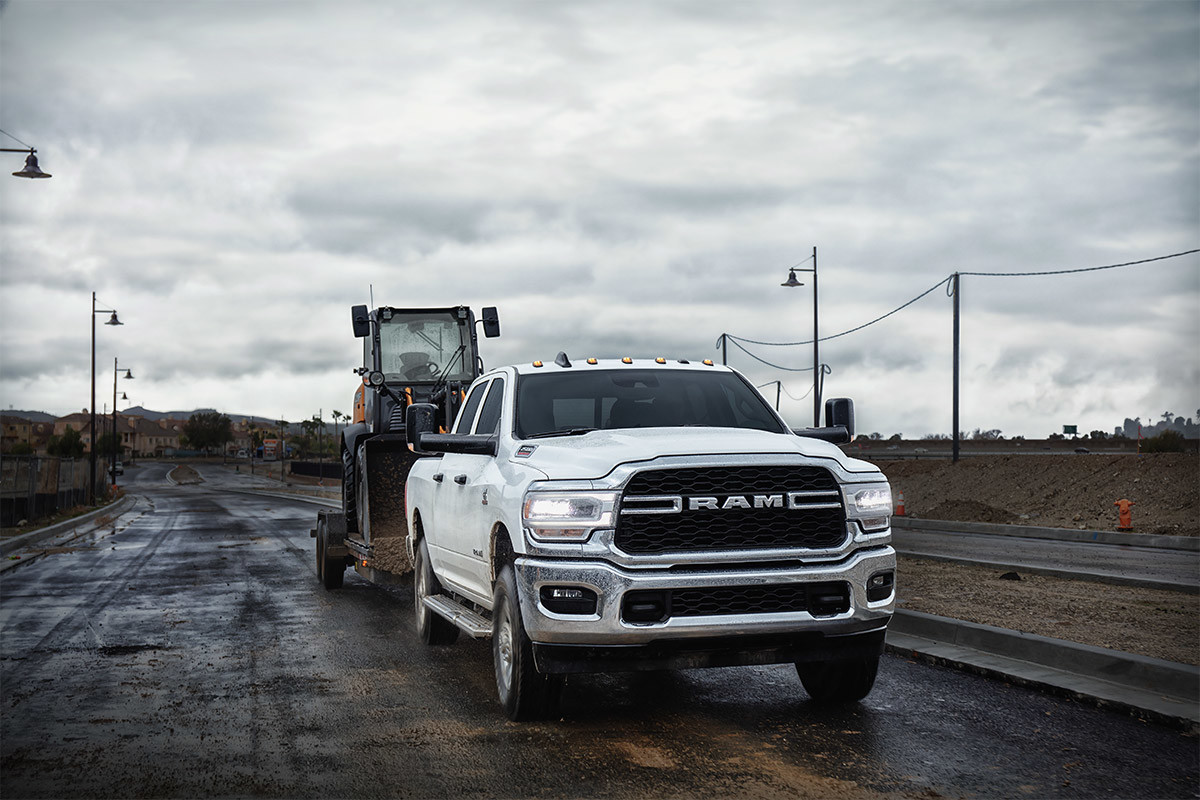 The 2020 Ram 2500 towing a crawler loader on a road