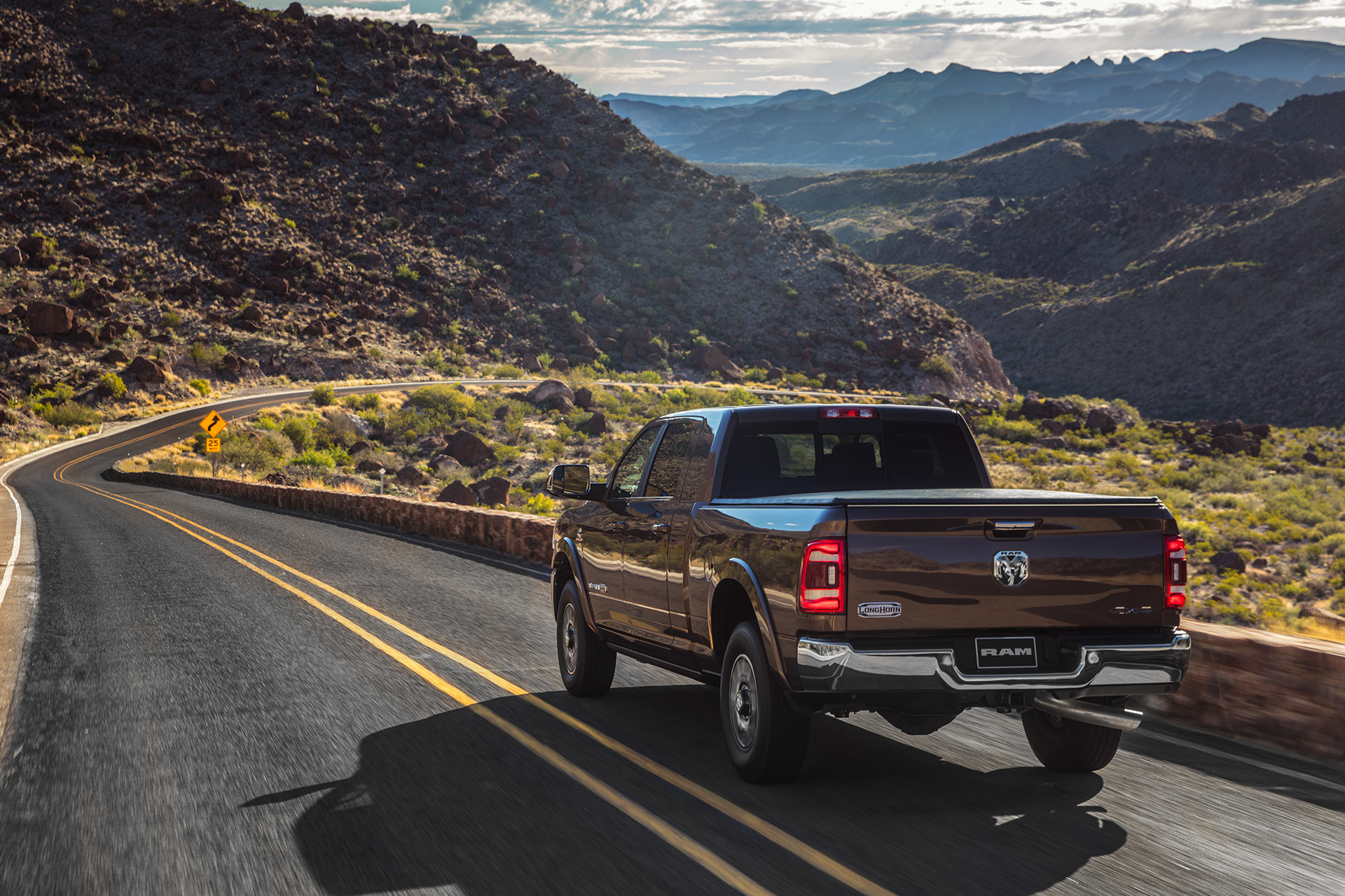 The 2020 Ram 2500 being driven on a country road beside mountains