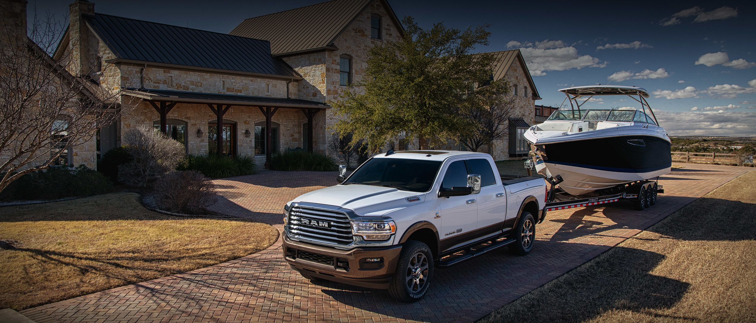 The 2020 Ram 2500 parked on a driveway while towing a boat