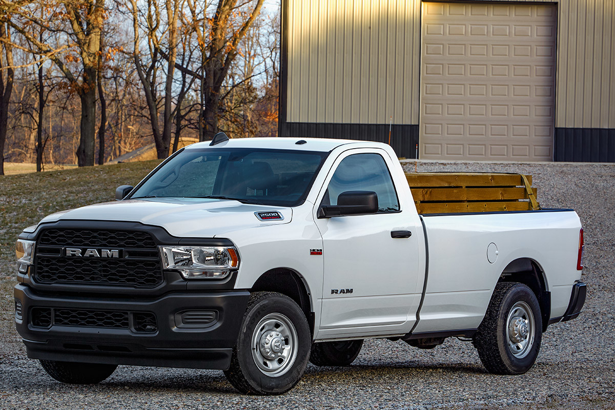 Ram 2500 blanc stationné devant un bâtiment avec des arbres en arrière-plan.