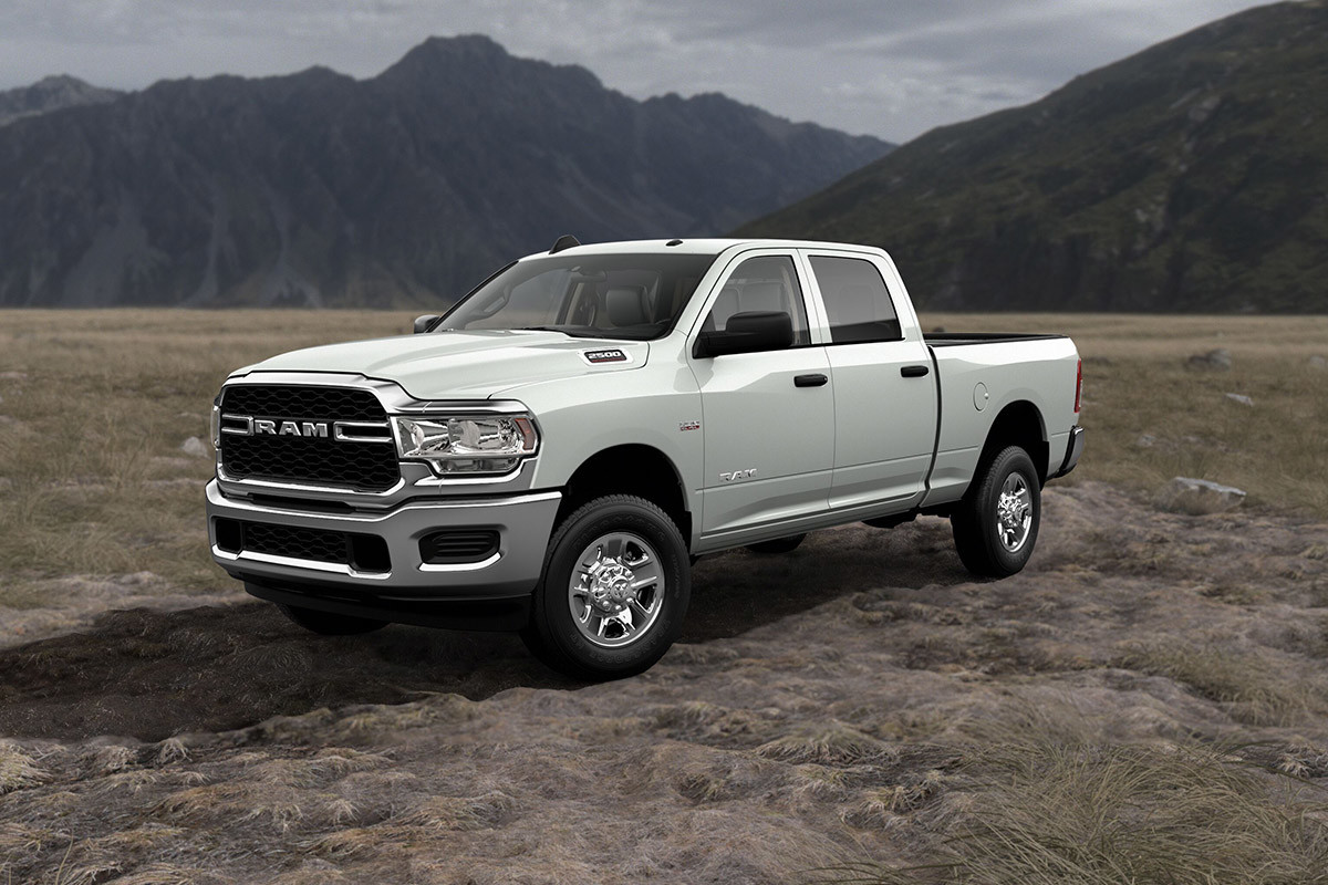 A white 2022 Ram 2500, parked on a grass field with mountains in the background.
