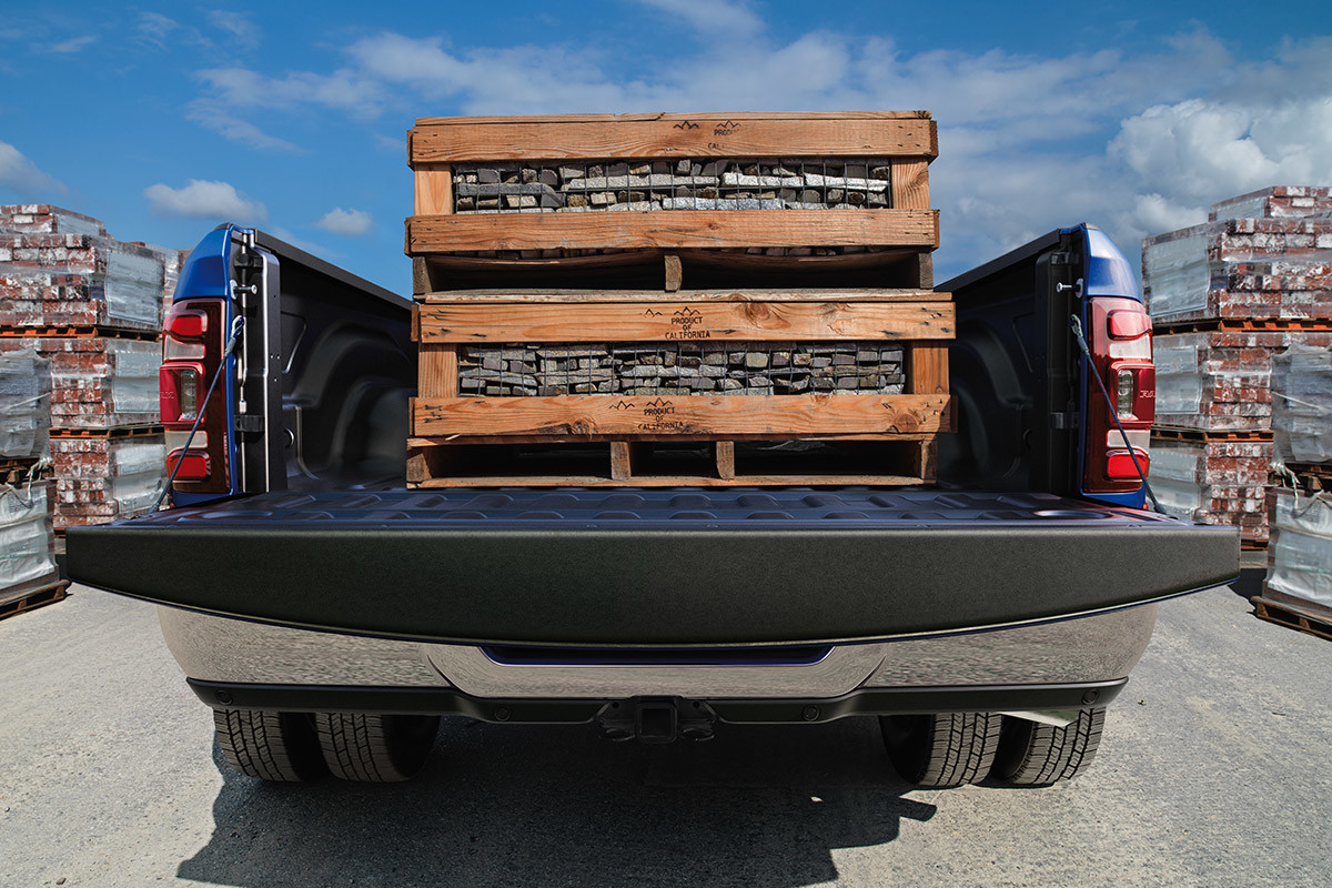 Blue 2020 Ram 3500 carrying wooden crates on its trunk with its tailgate open.