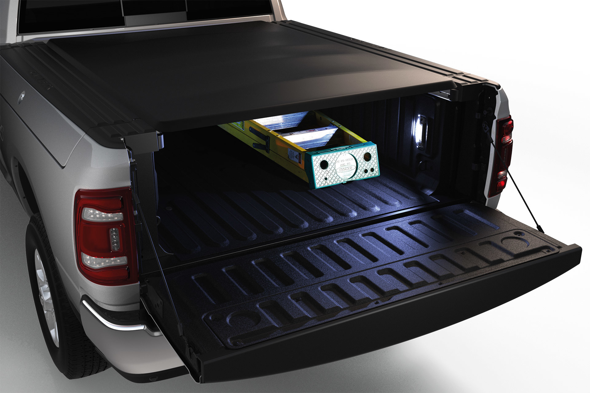 Silver 2020 Ram 3500 with its tailgate open revealing a ladder stored in its cargo bed with the side LED lights on.