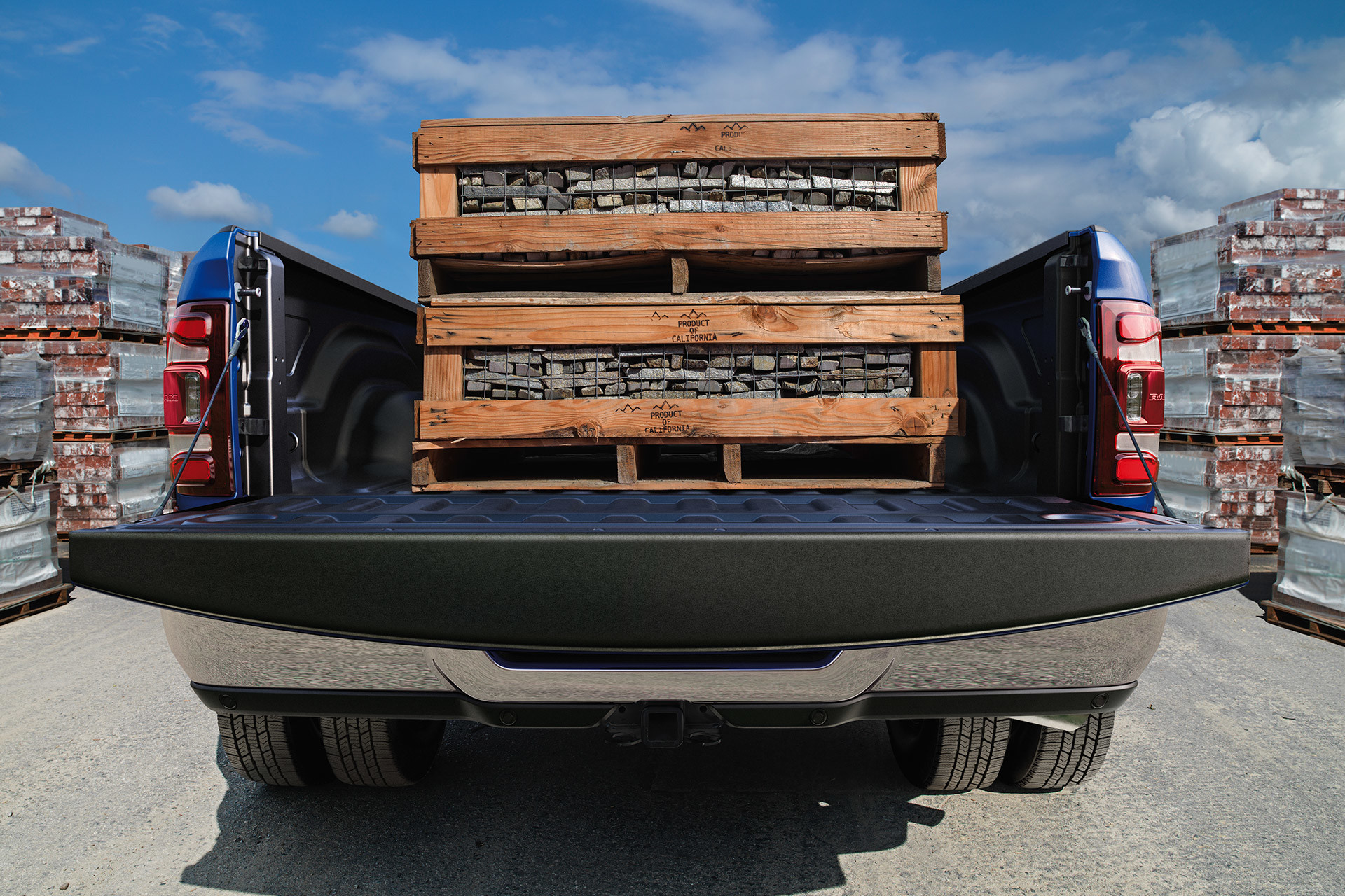 Alt Tag Blue 2020 Ram 3500 carrying wooden crates on its trunk with its tailgate open.