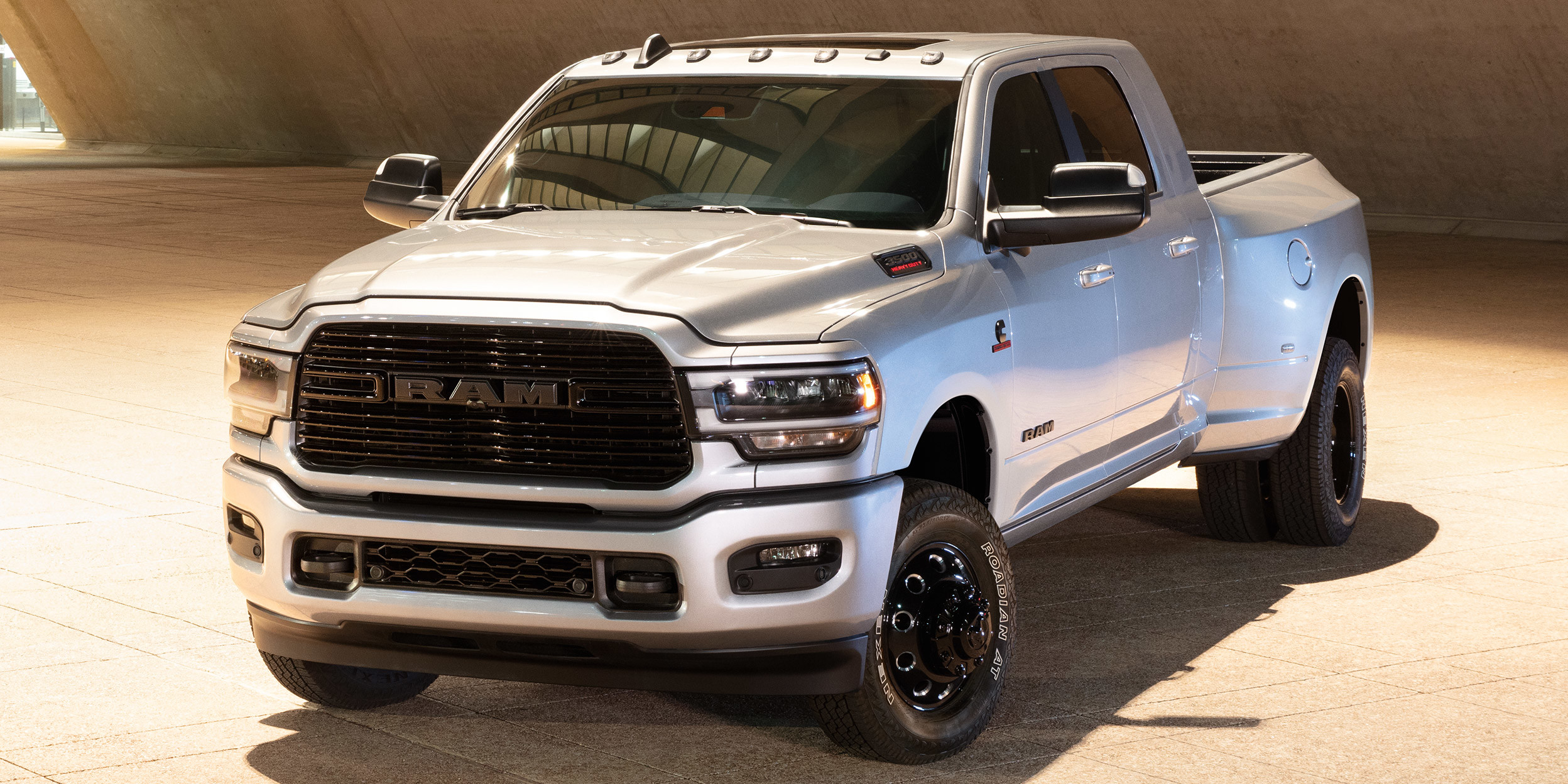 3500 HD Dually Big Horn gris acier argenté métallisé avec l’ensemble édition Night, garé à l’intérieur d’une structure de bâtiment.
