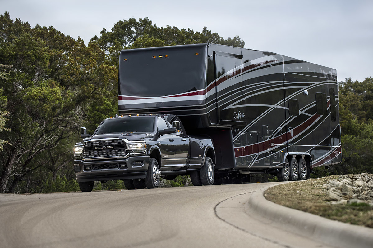 Black Ram 3500 towing a trailer on a path surrounded by trees.