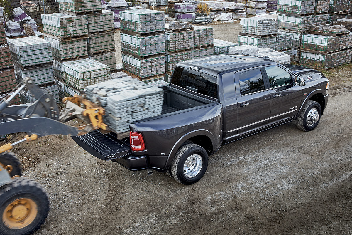 A front loader, loading the truck bed of a 2022 Ram 3500 with cargo.